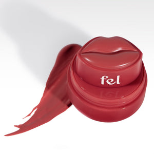Fel Beauty's Kissylips Lip and Cheek Balm Product with custom lip-shaped applicator, next to a glossy smear of product. 